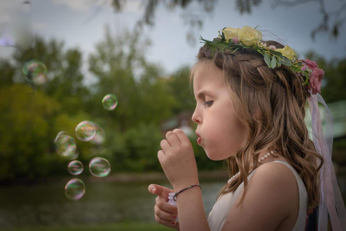 flower girl blowing bubbles outside