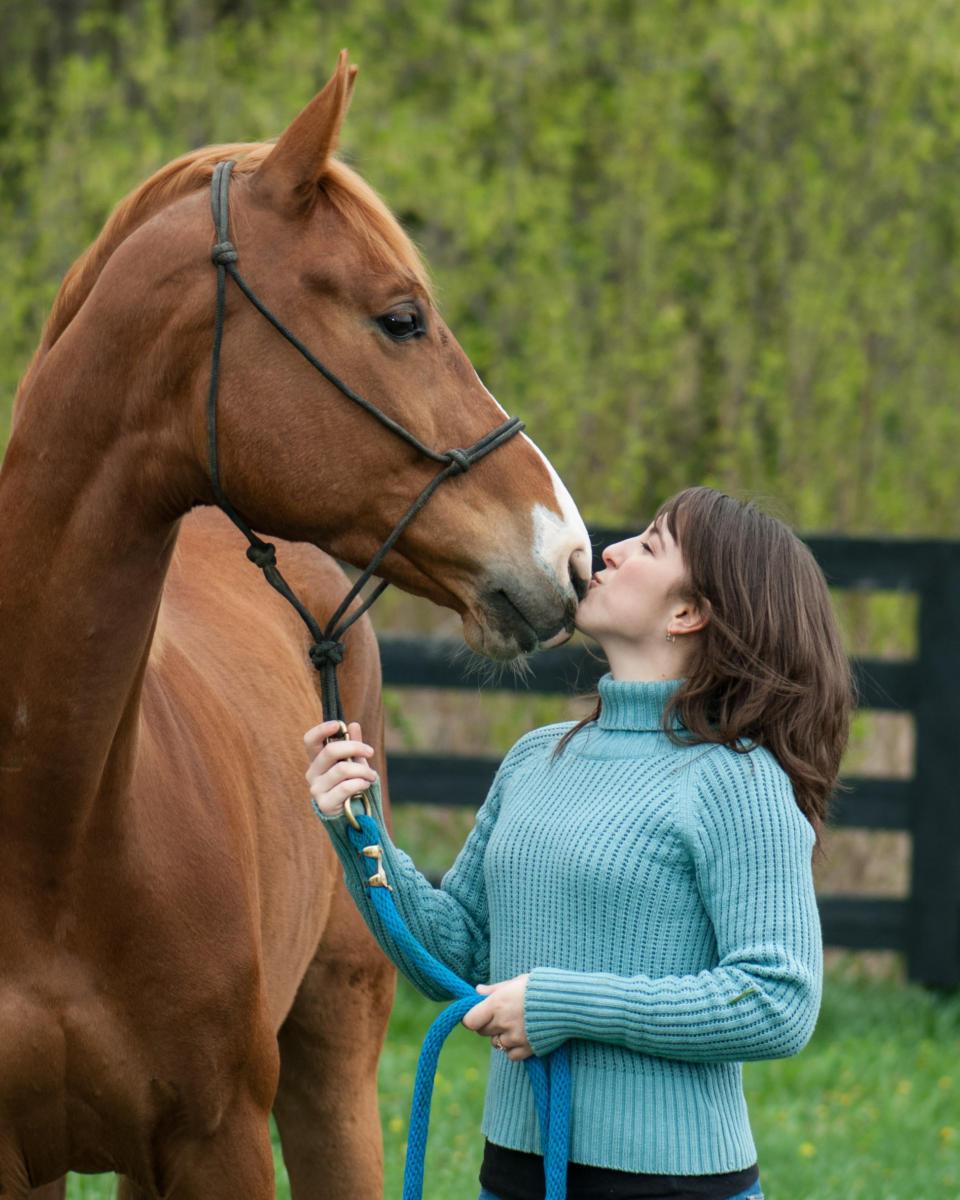 woman outdoors kissing pet horse