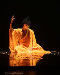 A seated dancer in a yellow Indian costume.