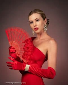 Portrait of a fashion model with a red gown and lace fan