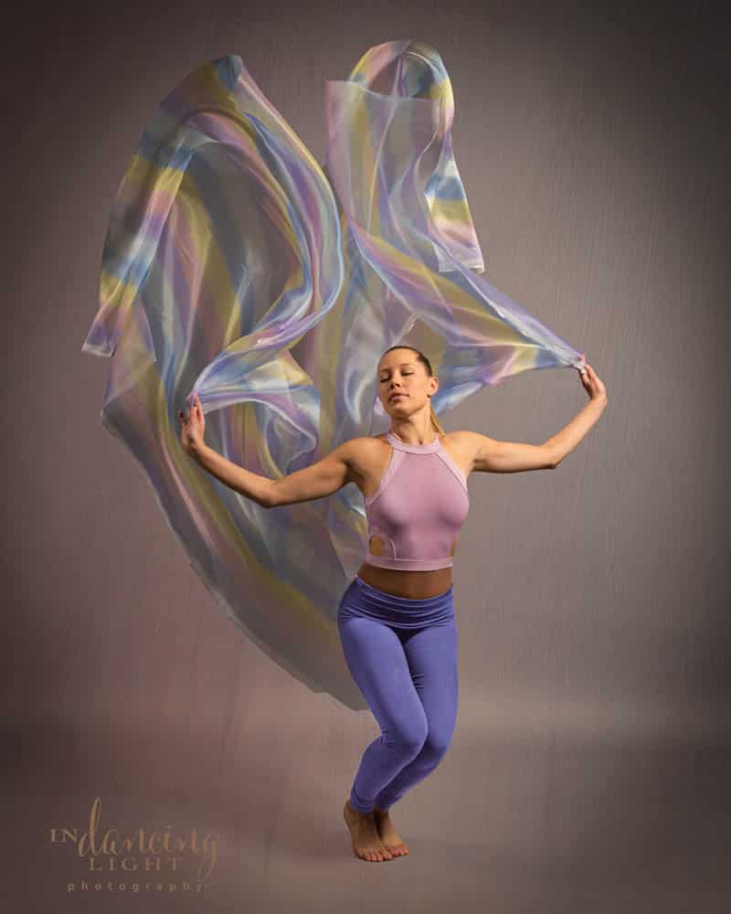 Female dancer tosses a colorful rainbow-colored fabric.