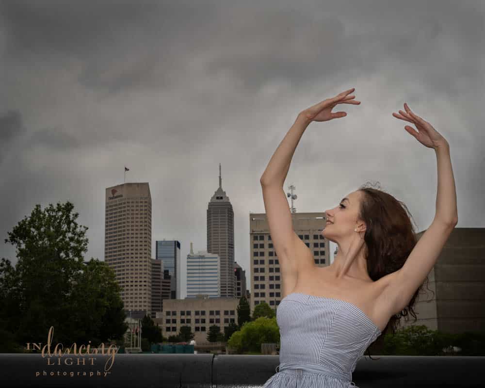 Ballerina with raised arms and Indianapolis skyline in the background