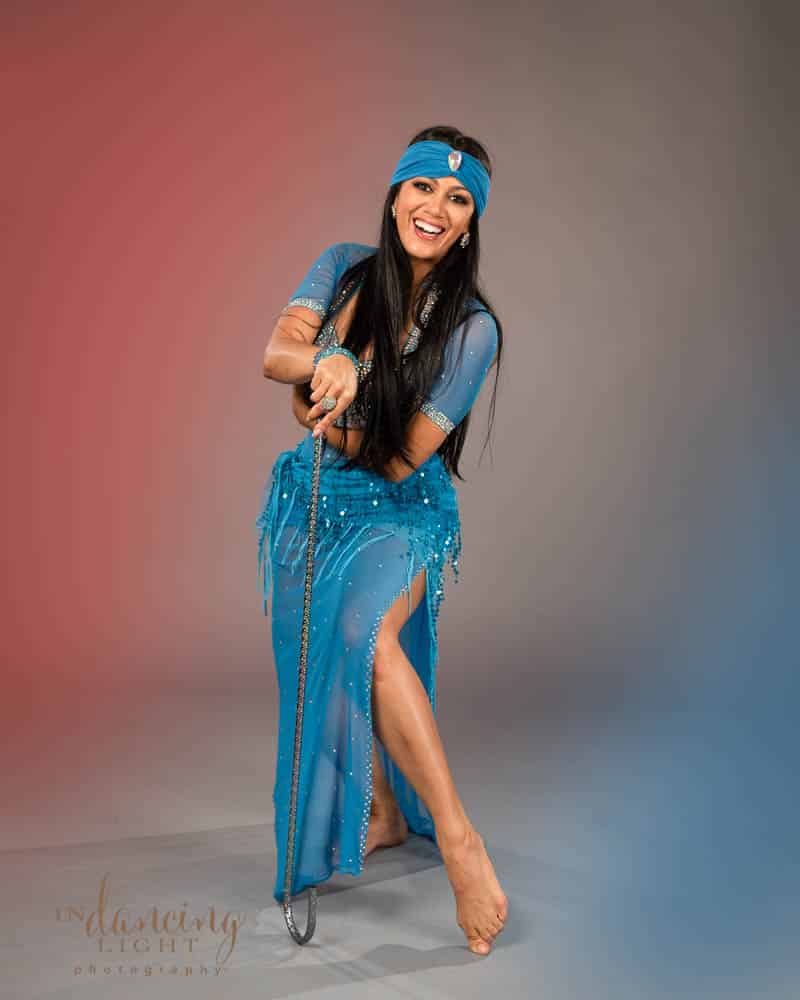 Mediterranean belly dancer in a blue dress holding a cane