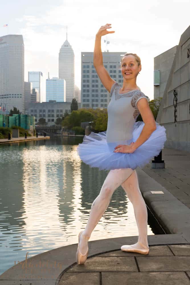 Ballerina dances along the Indianapolis canal walk with the city skyline in the background