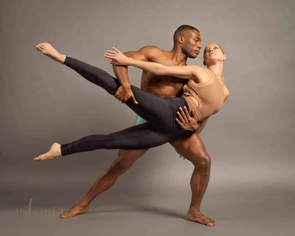 A male dancer holds a female dancer as they look at each other