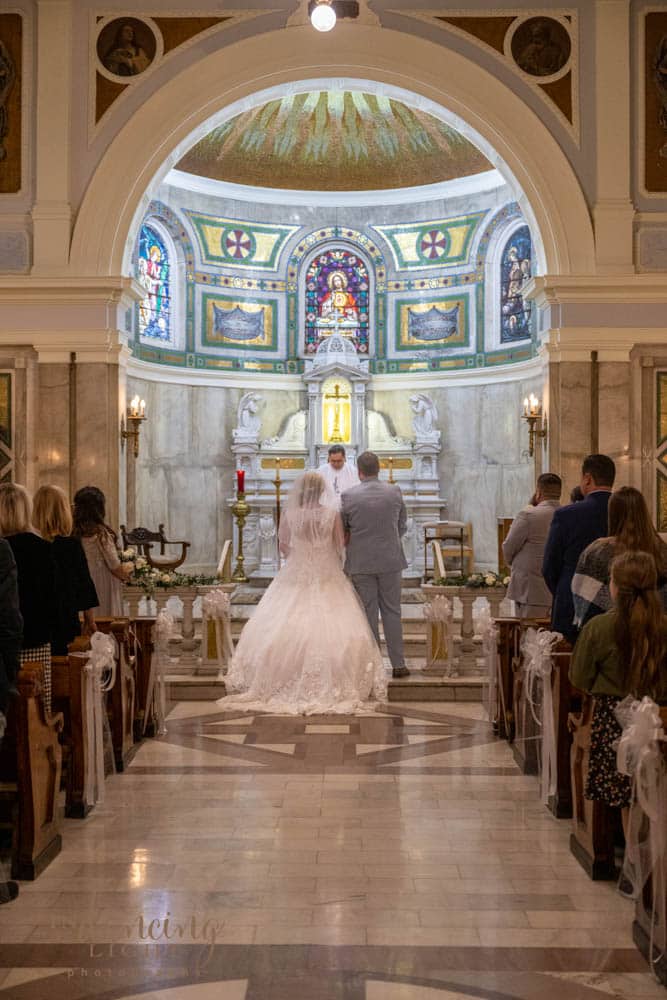 Bride and groom stand facing the front of the chapel during their wedding in the Indianapolis Cathedral.