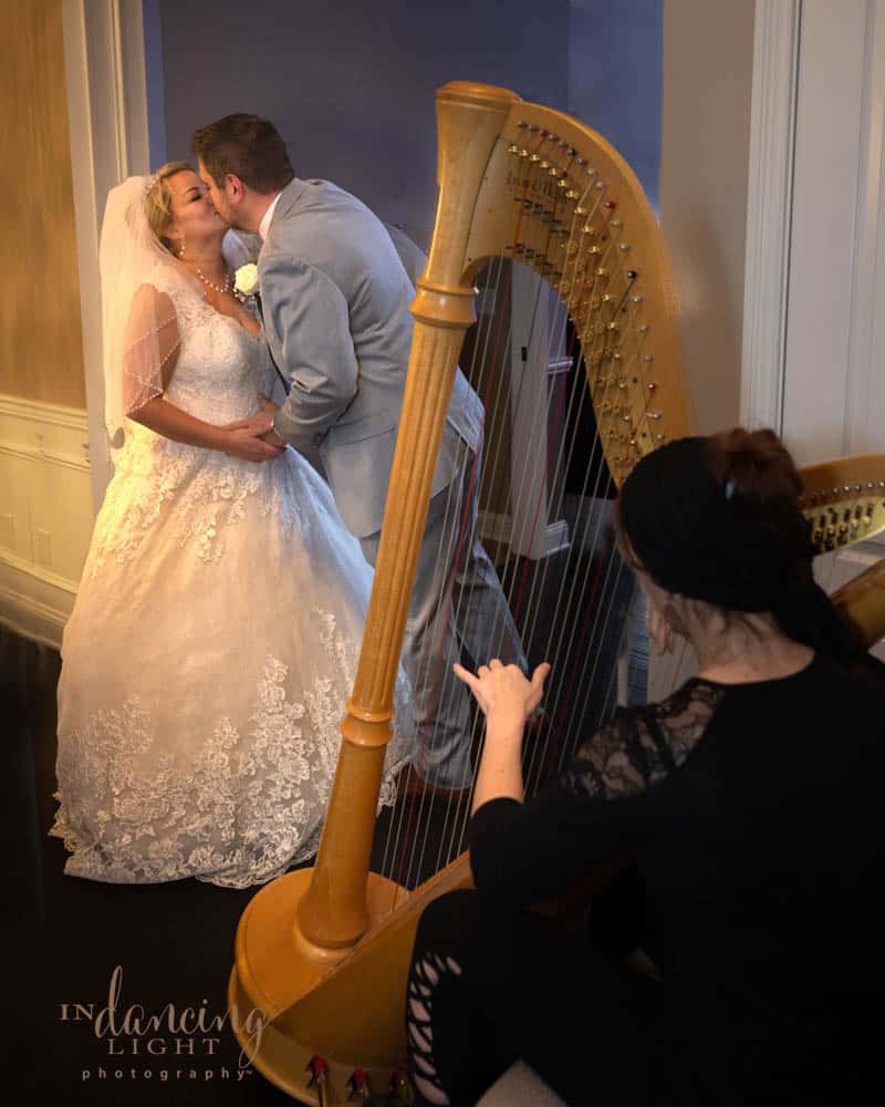 Wedding couple kiss with a harp in the foreground