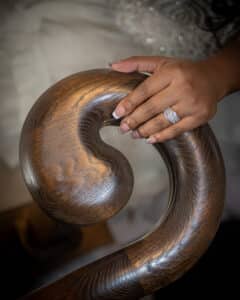 The bride's hand and wedding ring resting on the handrail