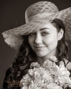 Monochrome headshot of Jessie with flowers and a hat