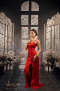 Jessie in red gown standing in a sun-draped room